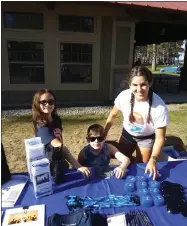  ?? ?? Many hands make light work: North Broad Street PTO member Jessica Kirley, far right, was hard at work with her daughter Allyson, eight, and son Ethan, seven, at the Madison County Dept. of Social Services table Saturday morning.