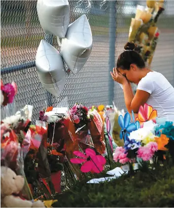  ?? PHOTO AFP ?? Une élève de l’école Marjory Stoneman Douglas se recueille devant un mémorial érigé à la mémoire de ses camarades décédés.