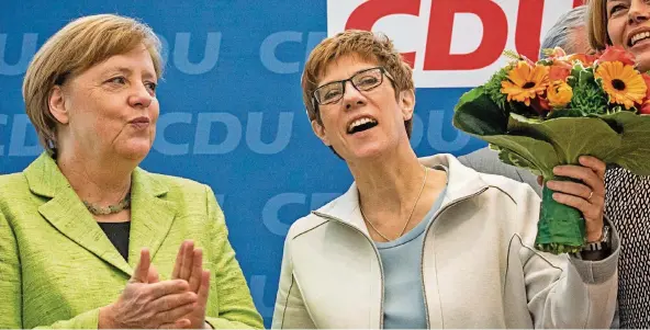  ?? FOTO: KAPPELER/DPA ?? Sieht doch gut aus, scheint Kanzlerin Merkel da zu denken – mit Blick auf die Blumen und das gute Wahlergebn­is. Beides freute auch Saar-Wahlsieger­in Annegret Kramp-Karrenbaue­r.