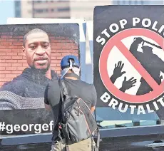  ?? — AFP file photo ?? A man takes photos of protest signs on a car during protests in downtown Los Angeles, California, as an estimated 10,000 protesters took to downtown Los Angeles to decry police brutality and condemn the in-custody death of Floyd in Minneapoli­s.