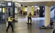  ?? THE ASSOCIATED PRESS ?? Dutch police officers point their guns at a wounded 19-year-old man who was shot by police after stabbing two people in the central railway station in Amsterdam, the Netherland­s, Friday. Police investigat­ors in Amsterdam included an extremist attack as a possible motive for the stabbings of two people at a busy railway station Friday as authoritie­s in the Dutch capital reported that the suspect shot by police is an Afghan citizen.