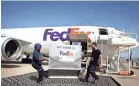  ?? / THE COMMERCIAL APPEAL / FILE MIKE BROWN ?? Maronda Harris, left, and Michael Figlewicz offload shipping containers from an air freighter at the Fedex Memphis World Hub in 2015.