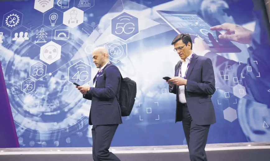  ?? ?? People walk by an advert for 5G at the 2024 Mobile World Congress (MWC), Barcelona, Spain, Feb. 27, 2024.