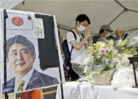  ?? Yomiuri Shimbun file photo ?? People offer prayers in Nara City in July at a floral tribute stand set up near the site of the fatal attack on former Prime Minister Shinzo Abe.