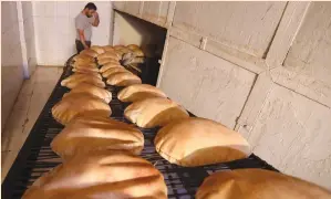  ?? (Mohamed Azakir/Reuters) ?? A WORKER stands near freshly baked bread at a bakery in Beirut last month.