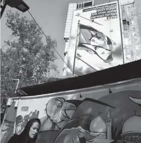  ?? / AP ?? A WOMAN walks past an anti-Israeli banner on a building at the Felestin Square in downtown Tehran, Iran on April 14, 2024.