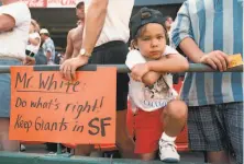  ?? Tom Levy / The Chronicle 1992 ?? A young Brandon Crawford stands next to his father, Mike (holding sign), at Candlestic­k Park in 1992.