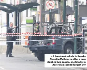  ??  ?? &gt; A burnt-out vehicle in Bourke Street in Melbourne after a man stabbed two people, one fatally, in Australia’s second-largest city