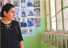  ?? AP ?? Farida Khalaf stands near posters of killed Yazidis in the school where the terrorists first imprisoned them in Kocho, Iraq.