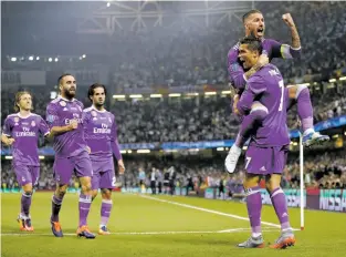  ?? FRANK AUGSTEIN/THE ASSOCIATED PRESS ?? Real Madrid’s Cristiano Ronaldo celebrates Saturday with Sergio Ramos, top, after scoring the opening goal during the Champions League final against Juventus at Millennium stadium in Cardiff, Wales. Real Madrid defended their title, winning 4-1.