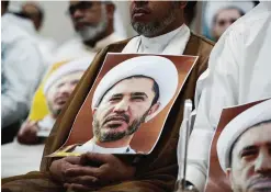  ??  ?? AZ ZINJ, Bahrain: A Bahraini man holds a placard bearing the portrait of Sheikh Ali Salman, head of the Shiite opposition movement Al-Wefaq, during a protest against his arrest, in the village of Zinj on the outskirts of the capital Manama. —AFP
