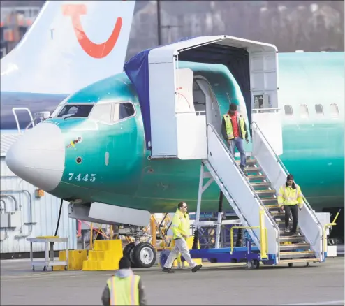  ?? Ted S. Warren / Associated Press ?? Workers walk down stairs from a Boeing 737 MAX 8 airplane being built for American Airlines at Boeing Co.'s Renton assembly plant on Wednesday in Renton, Wash. President Donald Trump said Wednesday that the U.S. is issuing an emergency order grounding all Boeing 737 Max 8 and Max 9 aircraft in the wake of the crash of an Ethiopian Airliner.