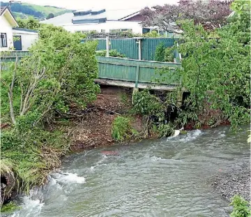  ?? MALCOLM SPARROW ?? A fence collapses into the Porirua stream at Tawa during flooding.