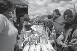  ?? KENT NISHIMURA/LOS ANGELES TIMES ?? Eddie Colbert, 71, second from right, and others pick up food and supplies from a food distributi­on event put on by Buffalo Community Fridge along Ferry Street, just blocks away from Tops Friendly Market, on Tuesday in Buffalo, N.Y.