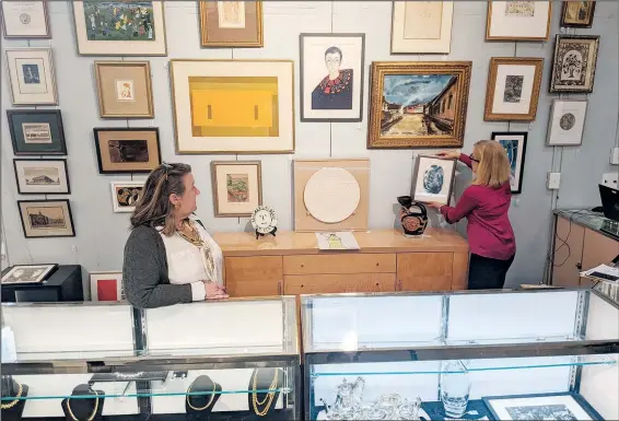  ?? (AP/Nathan Ellgren) ?? Elizabeth Haynie Wainstein (right) hangs up a piece of modern art belonging to the late Justice Ruth Bader Ginsburg on Monday inside Potomack Company Auctions in Alexandria, Va.