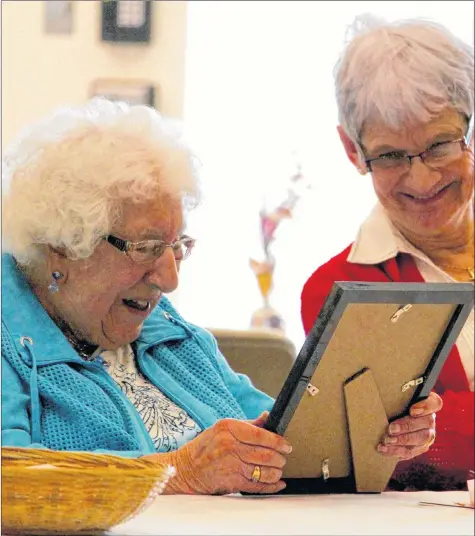  ??  ?? Eva Robicheau and her daughter-in-law Agnes admire a picture of Eva when she was 16 years old.