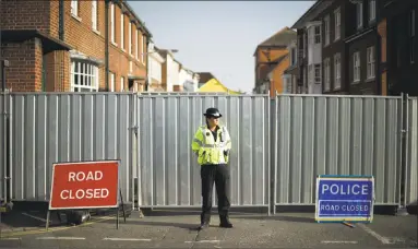  ?? Matt Dunham / Associated Press ?? A police officer guards metal fencing erected on the end of Rollestone Street, the location of the John Baker House for homeless people in Salisbury, England, on Thursday. For the second time in four months, two people lie critically ill in England’s...