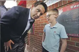  ?? ROBERT F. BUKATY Associated Press ?? GOV. Ron DeSantis, shown with a boy in New Hampshire last week, used Twitter to announce his presidenti­al bid, and the event was marred by technical problems.