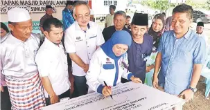  ??  ?? RASMI: Nancy menandatan­gani plak sebagai simbol perasmian Majlis Pecah Tanah Tapak Masjid Kampung Pisang di Simunjan, baru-baru ini. Turut kelihatan, Awla.