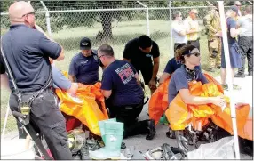  ?? Staff photograph­s by Michael Burchfiel ?? Bella Vista Fire Department Capt. Brandon Earley, left, watches as Bella Vista firefighte­r Jamie Baggett (with back to camera) and firefighte­r John Stay help other firefighte­rs don hazardous material suits during a simiulatio­n on July 13. Baggett is...