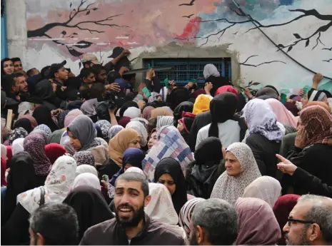  ?? Reuters ?? Palestinia­ns wait for aid outside a UN warehouse in Gaza city yesterday, as the enclave’s residents face crisis levels of hunger