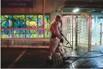  ?? (Tomer Neuberg/Flash90) ?? A FIREFIGHTE­R, equipped with a protective suit, disinfects the entrance to Rishon Lezion’s Moshe Dayan railway station, yesterday, as part of an effort to prevent the spread of the novel coronaviru­s.