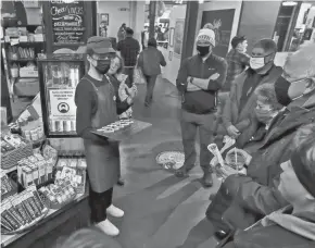  ?? NICOLAS GALINDO/THE COLUMBUS DISPATCH ?? Vito, a cheesemong­er with Black Radish Creamery, speaks to participan­ts of the Columbus Food Adventures about the slices of Parmstead on a tray during a tour in the North Market on Nov. 13