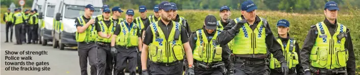  ??  ?? Show of strength: Police walk towards the gates of the fracking site