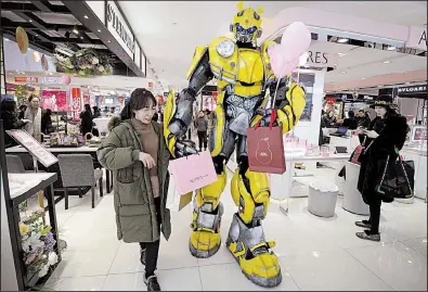  ?? AP ?? A person dressed as the Transforme­rs action figure Bumblebee helps a woman carry bags last week at a shopping mall in Handan, China. U.S. and Chinese officials resumed trade talks Tuesday in Washington.