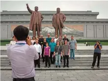 ??  ?? Tourists pose for a group photo before statues of late North Korean leaders Kim Il-Sung (left) and Kim Jong-Il (right), on Mansu hill in Pyongyang. — AFP photos