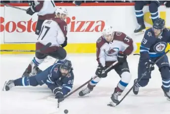  ?? John Woods, The Canadian Press ?? Winnipeg’s Mathieu Perreault, left, attempts to play the puck after getting checked by Colorado’s Tyson Jost during the Avs’ 6-1 loss Friday night in Winnipeg, Manitoba.