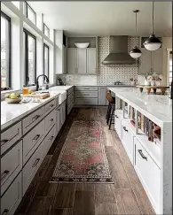  ?? AP/Grace Laird Photograph­y/Moore House Interiors ?? Interior designer Ashley Moore used a vintage Moroccan rug to add warmth and color to this kitchen. The rug’s appealingl­y worn look blends with the reclaimed wood floor.