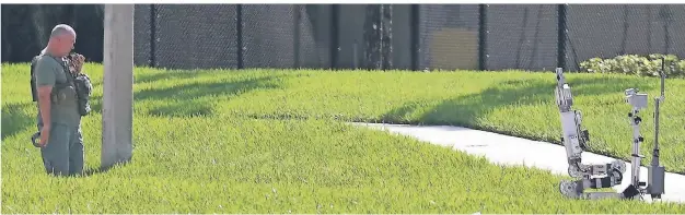  ?? FOTO: AFP ?? Sunrise, Florida: Ein Polizist und ein Roboter haben eine Briefbombe im Büro der Abgeordnet­en Debbie Wasserman Schultz untersucht.