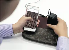  ?? KIYOSHI OTA / BLOOMBERG ?? An employee uses an Entrupy Inc. device, right, to verify the authentici­ty of a Louis Vuitton handbag. Entrupy says its camera magnifies objects 260 times.
