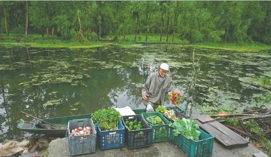  ?? TAUSEEF MUSTAFA/AFP VIA GETTY IMAGES ?? A farmer sells vegetables on the banks of Dal Lake during the government-imposed COVID-19 lockdown in Kashmir.