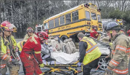  ?? JOHN SPINK PHOTOS /JSPINK@AJC.COM ?? Cobb County firefighte­rs extricated a man from his car that ended up under a school bus on Austell Road near McDuffie Road in Cobb County on Tuesday. The car rear-ended the bus just before 7:10 a.m. While the seven children and two adults on the bus...