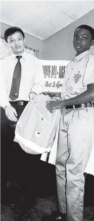  ?? PHOTO BY RASBERT TURNER ?? A representa­tive of Jamaica North-South Highway presents gifts to a student of the Golden Grove All-Age School.