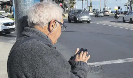  ?? RAFA ARJONES ?? Una persona jubilada utiliza el móvil apoyada en una farola de la calle, junto a un paso de cebra.