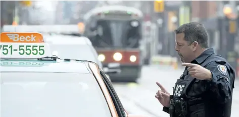  ?? DOUG IVES/THE CANADIAN PRESS ?? A police constable speaks to a taxi driver during the second day of the King Street Transit Pilot involving city streetcars on Monday in Toronto.