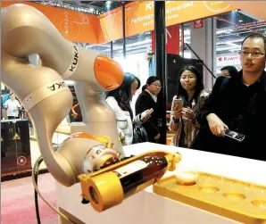  ?? HUANG ZHENGWEI / FOR CHINA DAILY ?? Kuka robot pours wine at a fair in Shanghai in November 2015.