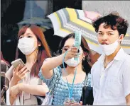  ?? REUTERS ?? Pedestrian­s uses a portable fan on the street during a heatwave in Tokyo, Japan.