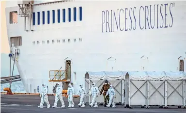  ?? CARL COURT/GETTY IMAGES ?? Personnel in protective clothing exit the Diamond Princess cruise ship Monday at Daikoku Pier in Yokohama, Japan, where people newly diagnosed with coronaviru­s are being treated as the vessel remains in quarantine.