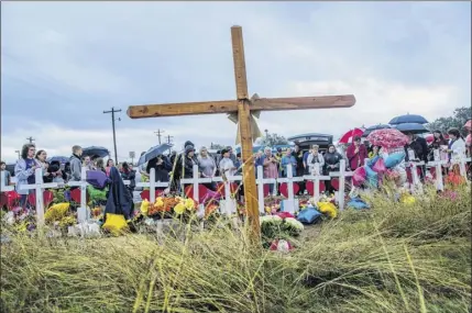  ?? Photos by Drew Anthony Smith / The New York Times ?? People gather in front of crosses at First Baptist Church in Sutherland Springs, Texas, which was transforme­d into a memorial to honor those who died on Nov. 12, 2017. At left, roses on chairs with the names of those killed during the shooting are part of the memorial. Places of worship have been targets of mass shootings in recent years, which has prompted some congregati­ons to take steps to increase security.