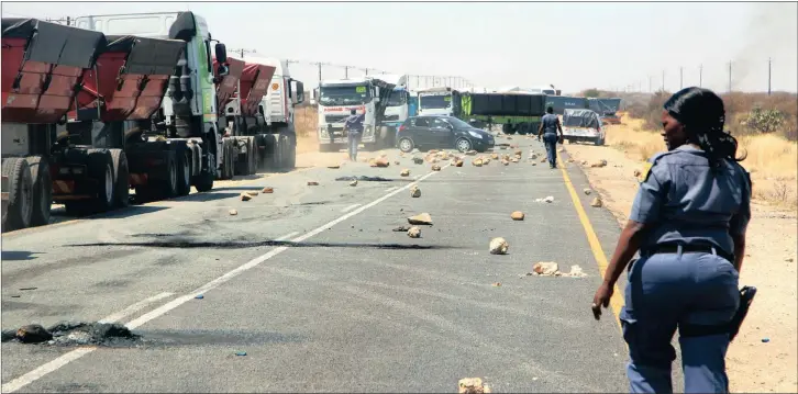  ?? PROTESTING: Soraya Crowie ?? Police officers are seen here clearing the R31 towards Postmansbu­rg after protesters from Longlands closed the intersecti­on. Community members insisted that their protest action would continue until the municipali­ty was fully functional.