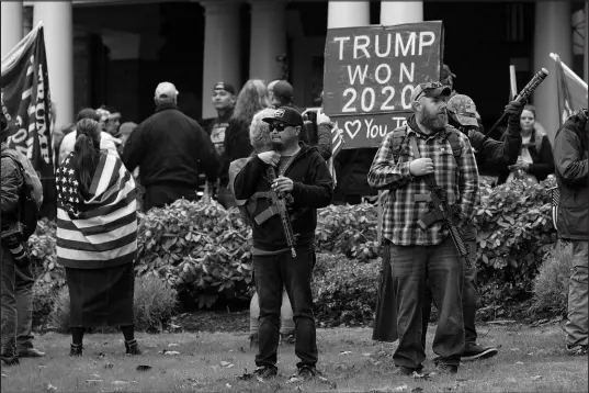  ?? TED S. WARREN / ASSOCIATED PRESS FILE (2021) ?? Two men stand armed with guns Jan. 6, 2021, in front of the Governor’s Mansion in Olympia, Wash., during a protest supporting then-president Donald Trump and against the counting of electoral votes in Washington, D.C.