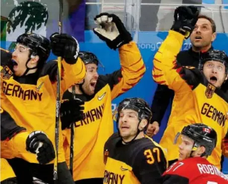  ??  ?? Canadian defenceman Mat Robinson of Calgary gets a front-seat view of the enthusiast­ic German celebratio­n after the underdogs defeated Canada 4-3 in their semifinal match to advance to the gold-medal game against the Olympic Athletes from Russia. Leah...
