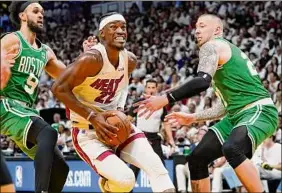  ?? Lynne Sladky / Associated Press ?? The Heat ‘s Jimmy Butler drives to the basket between Celtics teammates Derrick White, left, and Daniel Theis during Tuesday’s game in Miami.