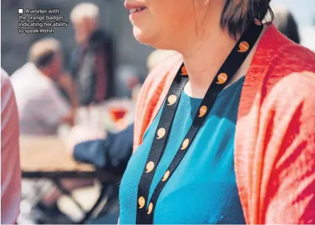  ??  ?? ■ A worker with the orange badges indicating her ability to speak Welsh