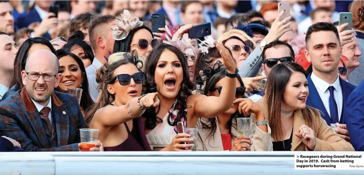  ?? Peter Byrne ?? > Racegoers during Grand National Day in 2019. Cash from betting supports horseracin­g
