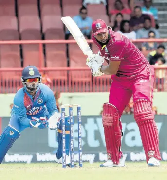  ?? ARNULFO FRANCO ?? West Indies batsman Kieron Pollard (right) makes a shot as India wicket-keeper Rishabh Pant looks on during their third T20 internatio­nal cricket match in Providence, Guyana, yesterday. Pollard struck 58 runs as the Windies lost by seven wickets.